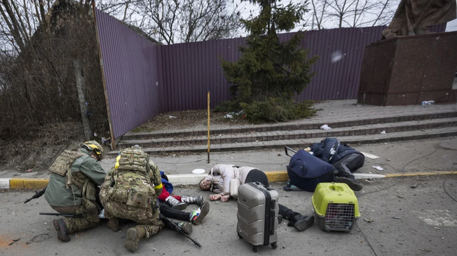 Servicios de emergencias tratan de socorrer a una familia que murió por el impacto de un cohete ruso en Irpin, mientras tratabamn de huir hacia Kiev (AP Photo/Andriy Dubchak)